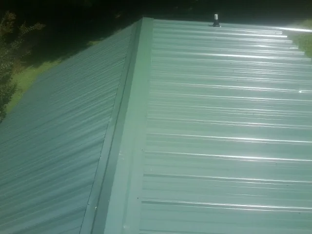 New green metal panels meeting at the ridge of a roof — Flat Roof Repair work by our crew in Spanaway