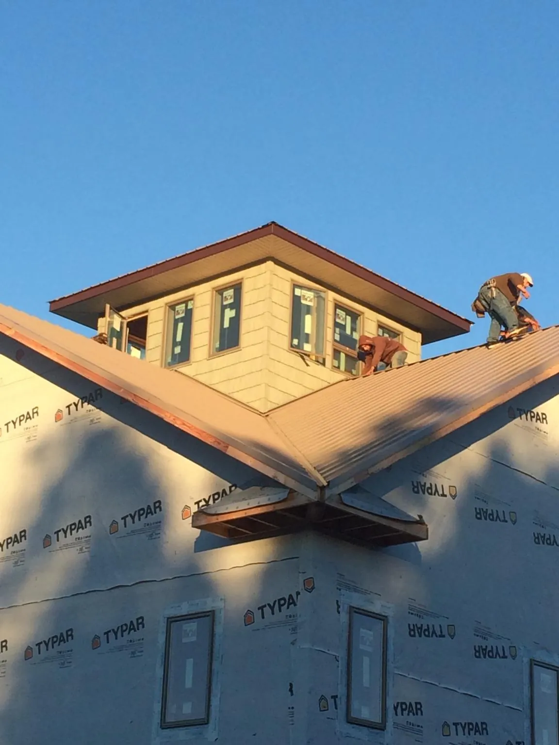 Roofers working around a rooftop cupola on a new metal roof at sunset — Roof Waterproofing in Spanaway by Roofing Brothers